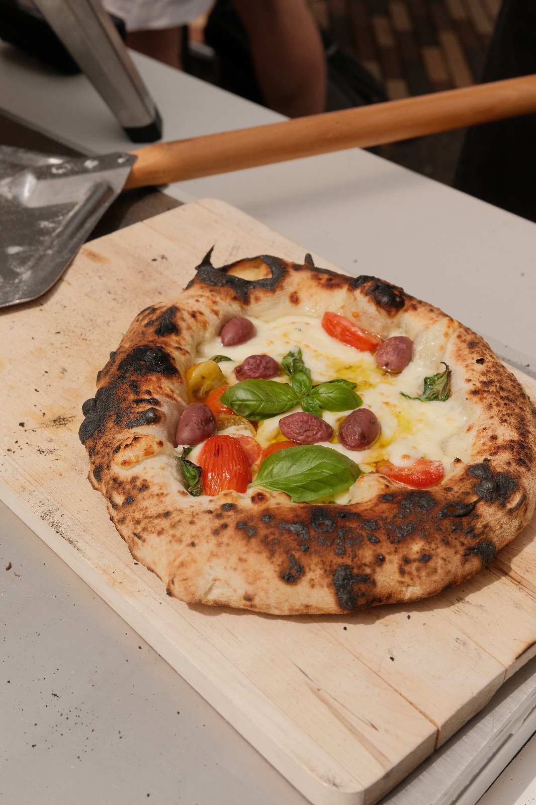 Frisch gebackene Pizza mit Oliven, Cocktailtomaten und Basilikum beim Bio-Event